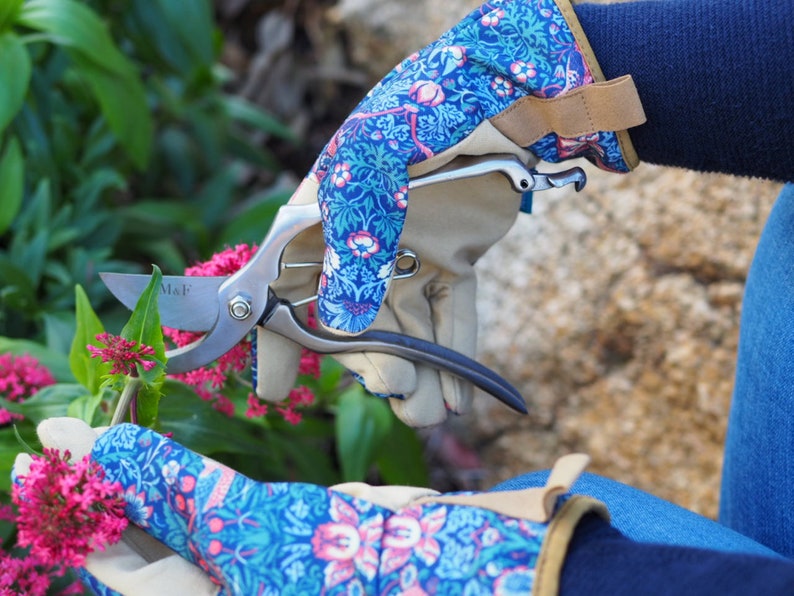 May include: A pair of blue and pink floral gardening gloves with a pair of pruning shears. The shears have a silver blade with the text "M&F" on the blade.