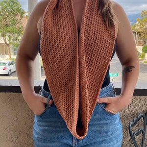 May include: A close-up of a person wearing a brown crocheted infinity scarf. The scarf is made with a simple stitch and has a relaxed, drapey look.