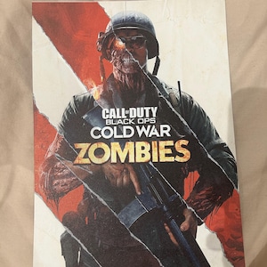 Könnte beinhalten: Werbebild für Call of Duty: Black Ops Cold War Zombies. Das Bild zeigt einen Zombie-Soldaten mit einer Maschinenpistole und den Titel des Spiels in fetter, orangefarbener und weißer Schrift.