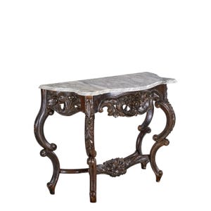 May include: A dark brown, ornate console table with a marble top. The table features carved floral and scrollwork details on the legs and apron. The marble top has a gray and white veined pattern.