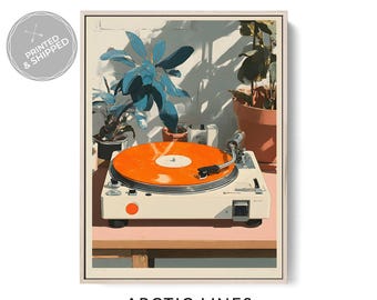 Puede incluir: Impresión artística enmarcada de un tocadiscos blanco con un disco naranja. La obra de arte incluye plantas en macetas con hojas azules y verdes, y el texto "ARCTIC LINES" en la parte inferior. La impresión está en un marco blanco.