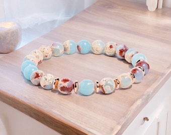 May include: A bracelet made of light blue and brown patterned beads with rose gold accents.