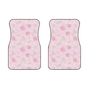 May include: A pair of rectangular car floor mats with rounded corners, featuring a light pink background patterned with small pink strawberries, white five-petaled flowers, pink circular blossoms, and thin green leaves with dark green stems.