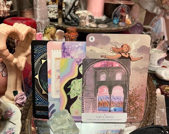 May include: A collection of tarot cards with various illustrations, including a woman with flowing hair and a card with the text "TAKE A BREAK". The cards are arranged with crystals, candles, and other spiritual items, creating a mystical aesthetic.