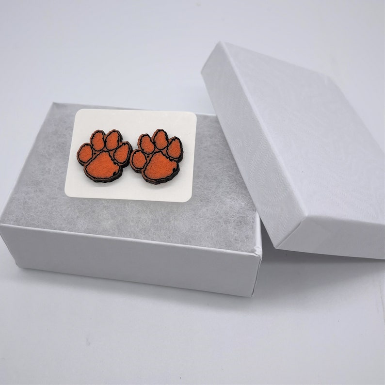 May include: A pair of orange and black paw print earrings in a white gift box.