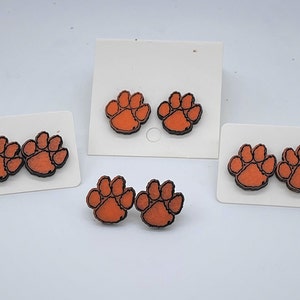May include: Three sets of orange and black paw print earrings. Each set has two earrings.