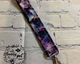 May include: A purple and blue floral patterned fabric key chain with a silver swivel clasp.