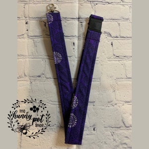 May include: Purple lanyard with a white swirl pattern. The lanyard has a silver clip and a black buckle.