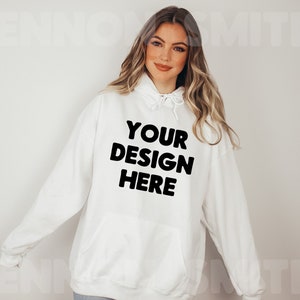 Może przedstawiać: Biała bluza z kapturem z nadrukiem "YOUR DESIGN HERE" w kolorze czarnym.