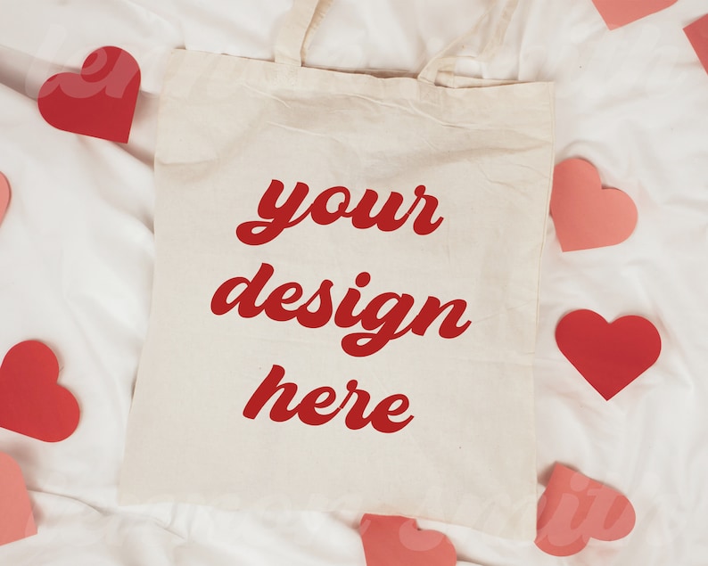 May include: A white tote bag with red text that says "your design here" on a white background. The bag is surrounded by pink and red hearts.