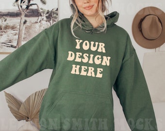 May include: A green hooded sweatshirt with the text "YOUR DESIGN HERE" in a light yellow color. The text is in a retro font style.