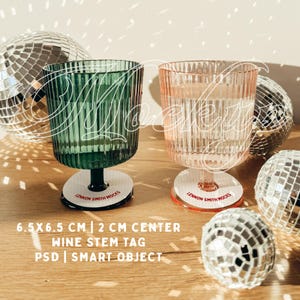 Peut inclure: Deux étiquettes pour pied de verre à vin avec un fond blanc et un texte rouge qui dit "LENNON SMITH MOCKS". Les étiquettes mesurent 6,5 cm sur 6,5 cm et ont un centre de 2 cm. Les étiquettes sont placées sur deux verres à vin transparents à motif côtelé. Un verre est vert et l'autre est rose. Les verres sont posés sur une surface en bois avec des boules à facettes en arrière-plan.