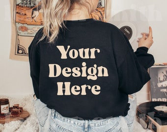 May include: A black long-sleeved sweatshirt with the text "Your Design Here" in a light brown colour.