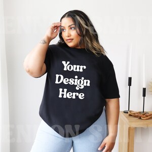 May include: A black oversized t-shirt with the text "Your Design Here" in white. The shirt is being modeled by a person with long dark hair.