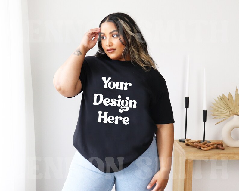 May include: A black oversized t-shirt with the text "Your Design Here" in white. The shirt is being modeled by a person with long dark hair.