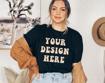 May include: A black t-shirt with the text "YOUR DESIGN HERE" in a retro font printed in beige.