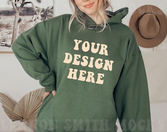 May include: A dark green hooded sweatshirt with the text "YOUR DESIGN HERE" in a retro font on the front.