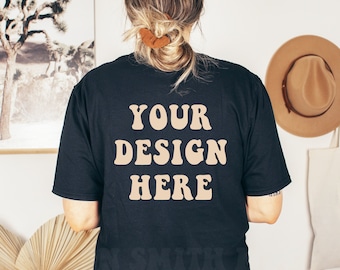 Pode incluir: Uma camiseta preta com o texto "YOUR DESIGN HERE" impresso em marrom claro nas costas.