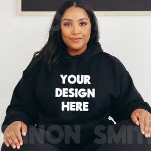 K&ouml;nnte beinhalten: Ein schwarzer Kapuzenpullover mit dem Text "YOUR DESIGN HERE" in wei&szlig; auf der Vorderseite.