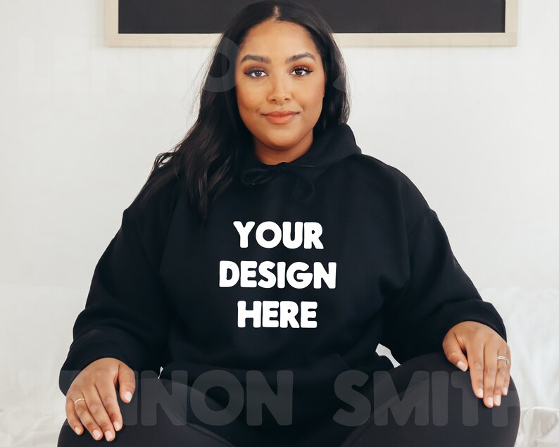K&ouml;nnte beinhalten: Ein schwarzer Kapuzenpullover mit dem Text "YOUR DESIGN HERE" in wei&szlig; auf der Vorderseite.
