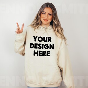 Może przedstawiać: Kremowa bluza z kapturem z czarnym nadrukiem "YOUR DESIGN HERE".