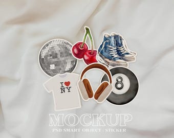 May include: A set of stickers featuring a disco ball, a pair of blue trainers, a red cherry, a pair of headphones, and a black and white eight ball. The stickers are on a white fabric background.