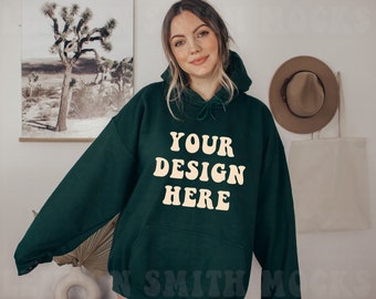 May include: A dark green hooded sweatshirt with the text "YOUR DESIGN HERE" in a light yellow font.