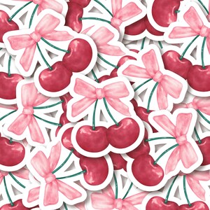 K&ouml;nnte beinhalten: Ein Muster aus roten Kirschen mit rosa Schleifen auf wei&szlig;em Hintergrund. Die Kirschen sind in Aquarelltechnik gezeichnet.