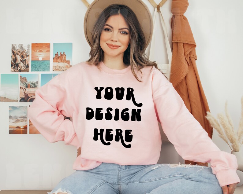 May include: A pink sweatshirt with the text "YOUR DESIGN HERE" in black, retro-style lettering.