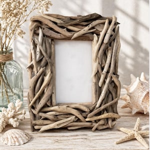 May include: A rectangular picture frame crafted from natural driftwood pieces. The frame has a light brown color and a rustic, beachy aesthetic. Decorative elements include a seashell, starfish, and a vase with dried flowers, creating a coastal theme.