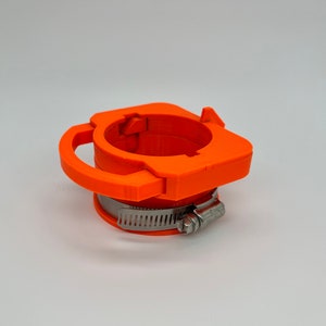 May include: Orange plastic pipe clamp with a metal tightening band. The clamp has a lever for easy tightening.