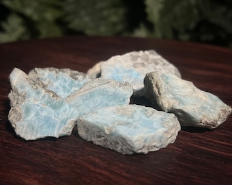 May include: A group of blue and gray  chalcedony stones with a shimmering effect. The stones are rough and have a natural, unpolished look.