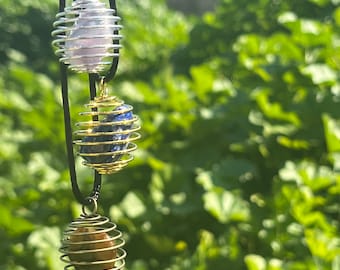 May include: Three crystal cage pendants with different colored stones. The top pendant has a pink stone, the middle pendant has a blue stone, and the bottom pendant has a brown stone.
