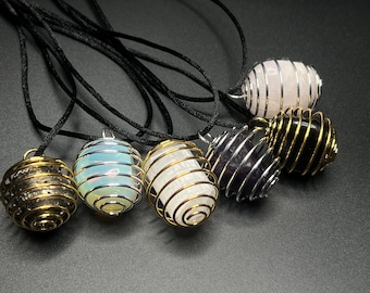 May include: Six crystal caged pendants on black cords. The crystals are clear, white, pink, purple, and black. The cages are made of silver wire.