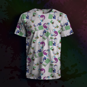 Può includere: T-shirt bianco con un motivo ripetuto di anatre dei cartoni animati con occhiali da sole. Le anatre sono ambientate su uno sfondo di forme geometriche in verde, viola e blu. La maglietta ha maniche corte e girocollo.