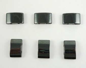 May include: Six black rectangular beads with a shiny finish. The beads have two holes on each side.