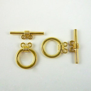 May include: Gold-toned metal toggle clasp with a round ring and a bar with two loops. The clasp is used for jewelry making.