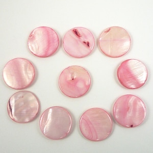 May include: A collection of ten pink, round, shell beads. The beads have a pearlescent sheen and varying shades of pink, with some showing darker pink swirls and patterns. The beads are arranged in a circular pattern on a white background.