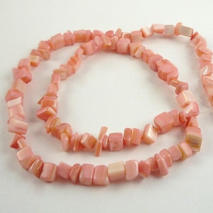 May include: A strand of pink and white shell beads, with a square shape, strung on a clear thread.