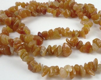 May include: A strand of orange and yellow chip gemstone beads. The beads are irregular in shape and have a natural, rough texture.