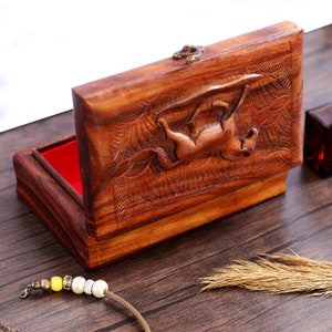 May include: A wooden box with a carved horse design on the lid. The box is open and has a red velvet lining.