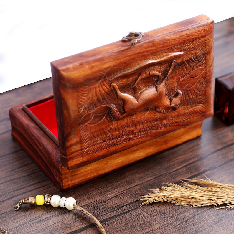 May include: A wooden box with a carved horse design on the lid. The box is open and has a red velvet lining.