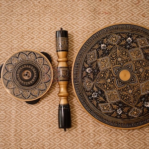 May include: A set of three decorative wooden pieces with intricate, symmetrical patterns in black and gold. The set includes a round table top, a smaller circular piece, and a central support column, all with detailed designs.