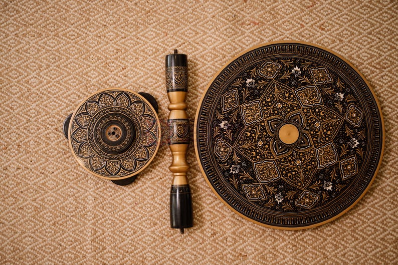 May include: A set of three decorative wooden pieces with intricate, symmetrical patterns in black and gold. The set includes a round table top, a smaller circular piece, and a central support column, all with detailed designs.