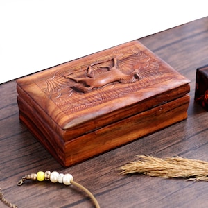 May include: A wooden box with a carved design of a horse on the lid. The box is made of dark wood and has a natural finish.