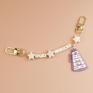 Dije de megáfono para animadoras, dije de cordón para zapato, dije para bolso, dije para mochila, dije de espíritu animador, regalo de espíritu animador para mamá animadora.
