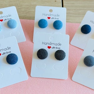 May include: Six pairs of denim fabric stud earrings displayed on white cards. Each card has the text "Handmade with love" printed on it.