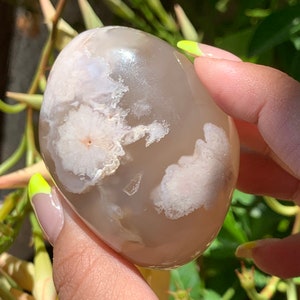 May include: A smooth, gray agate stone with white and pink patterns. The stone is polished and has a natural, organic shape.