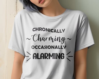 Puede incluir: Una camiseta blanca con texto negro que dice "Chronically ~Charming~ Occasionally ALARMING".