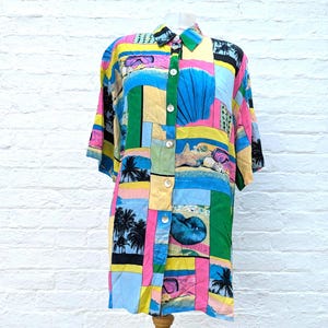 Può includere: Una camicia a maniche corte con abbottonatura frontale caratterizzata da un vivace design patchwork con scene di spiagge tropicali, palme, conchiglie e maschere da snorkeling nei toni del giallo, rosa, blu e verde. Colletto classico e bottoni bianchi.